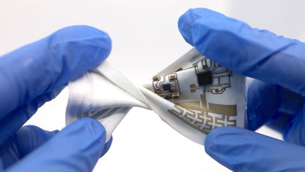 Pictured is a stretchable wearable devices incorporated on a newly developed material substrate that can adjust its dielectric properties to counter the disruptive effects of motion on interfacing electronics. The performance of the system was tested under various types of deforming motions, including twisting